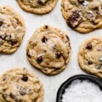 The Best Chocolate Chip Cookies topped with sea salt on a gray background.