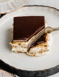 A fork cutting into a square of chocolate topped Chocolate Eclair Cake.