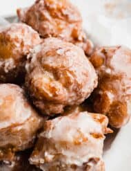 A stack of round fried peach fritters covered in a glaze.