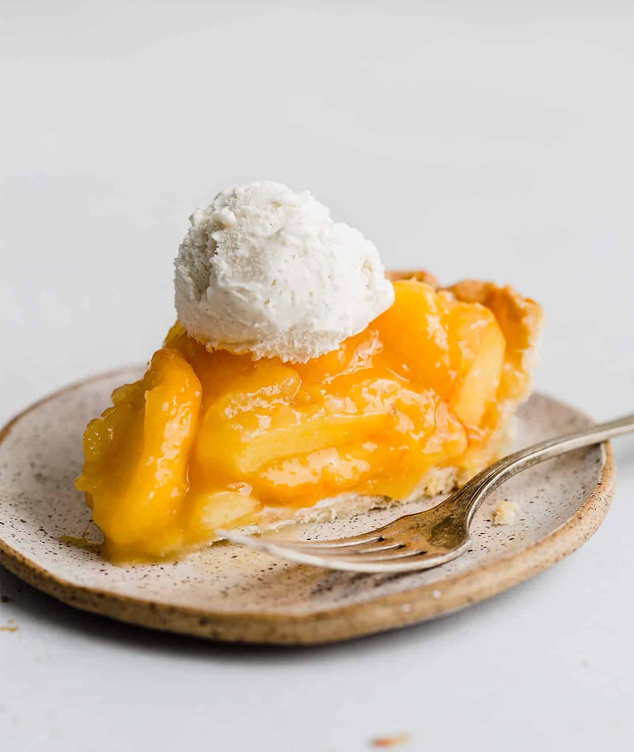 A scoop of vanilla ice cream on a slice of fresh peach pie.