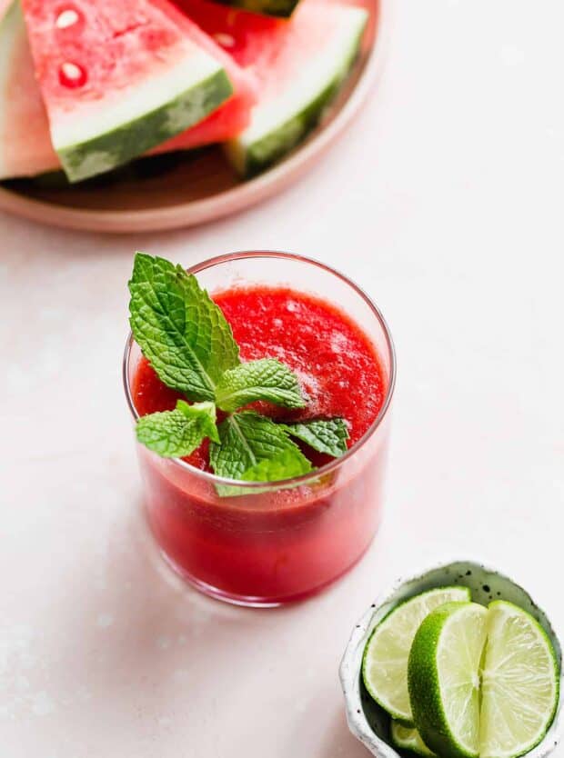 A glass of watermelon juice with a sprig of fresh mint for garnish.