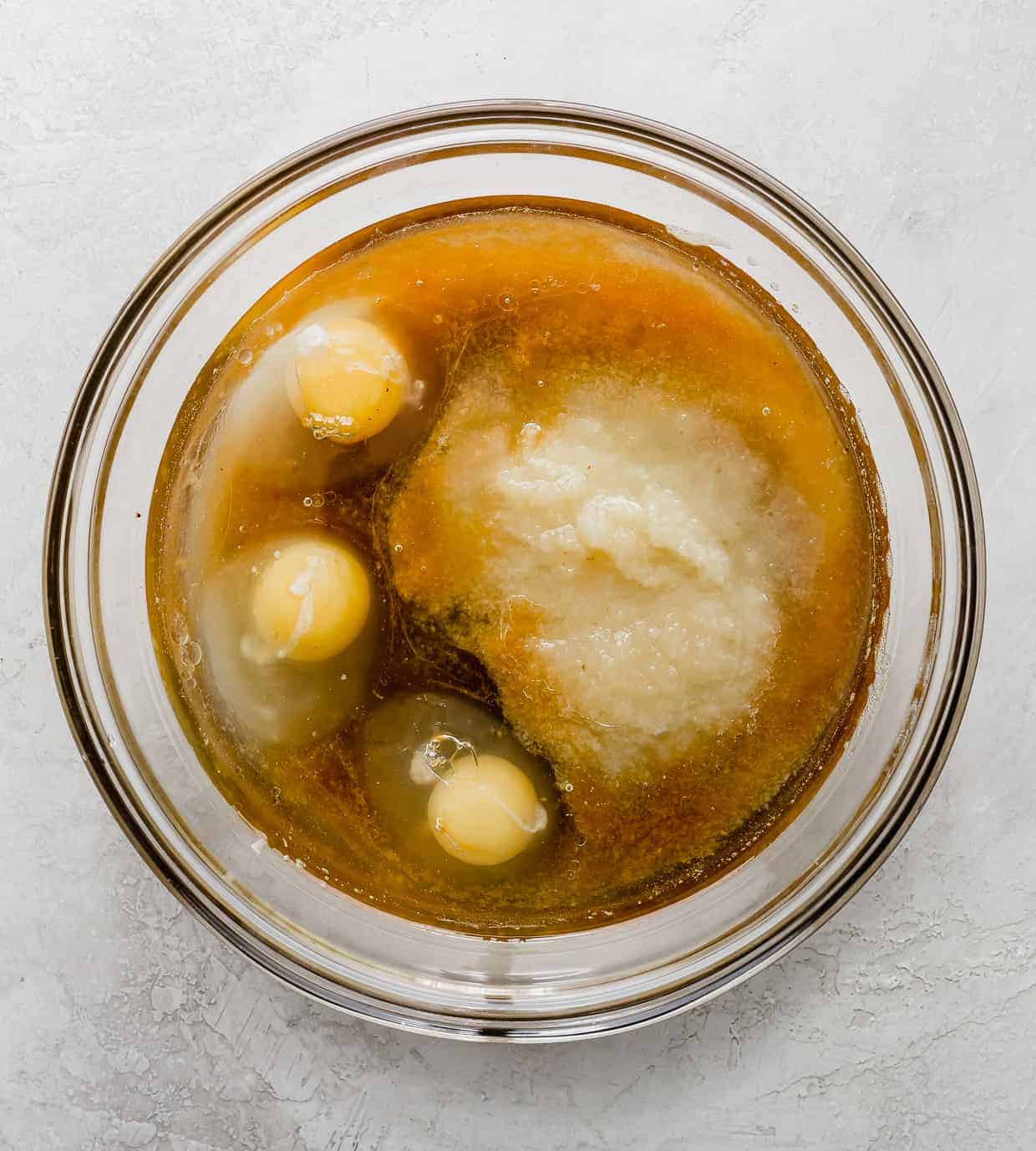 "Wet ingredients" in a glass bowl, consisting of 3 eggs, oil, apple sauce and vanilla.