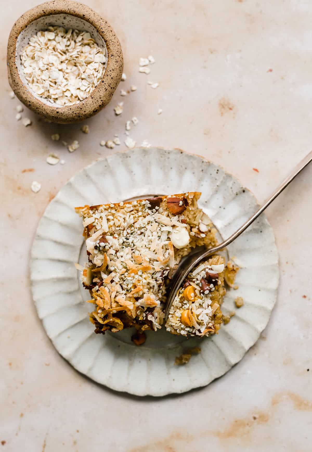 A square of Baked Oatmeal Cake on a plate with a fork cutting into the corner of the slice.