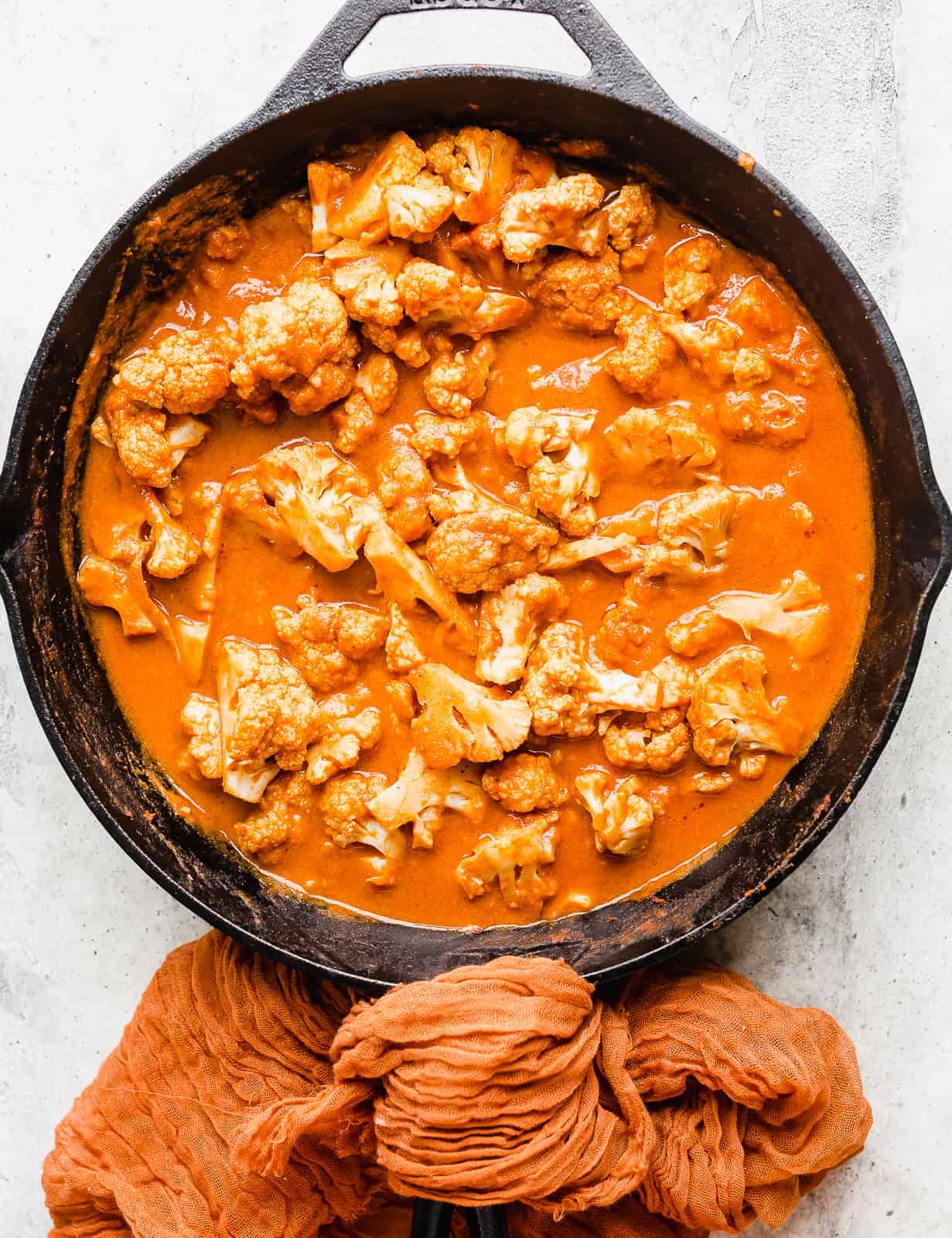 A black skillet full of orange colored Indian Butter Cauliflower.