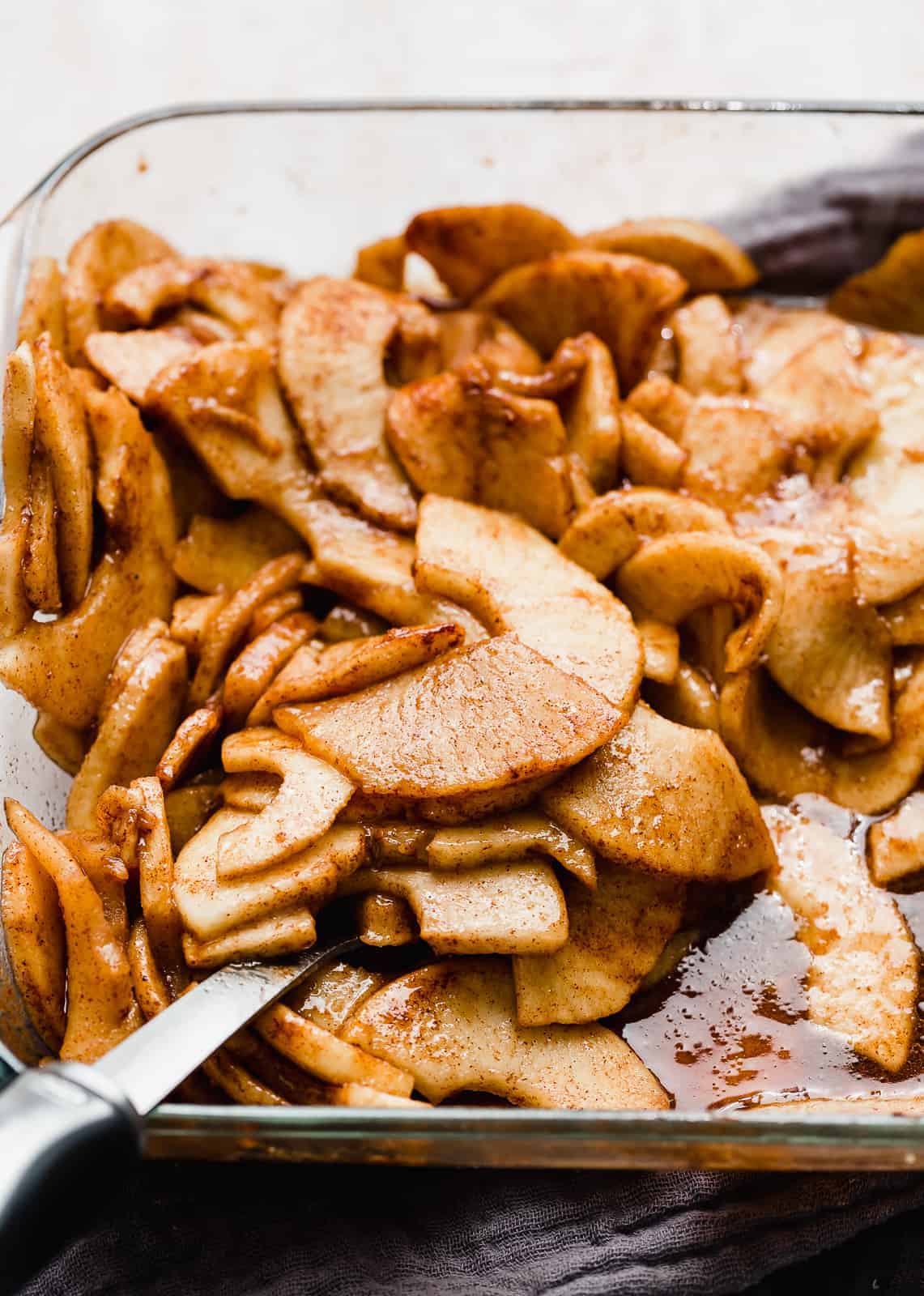 Thinly sliced baked cinnamon apples in a baking dish.