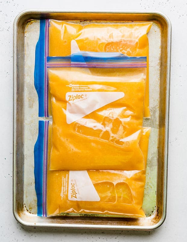 Three freezer-safe quart sized bags full of peach punch juice.
