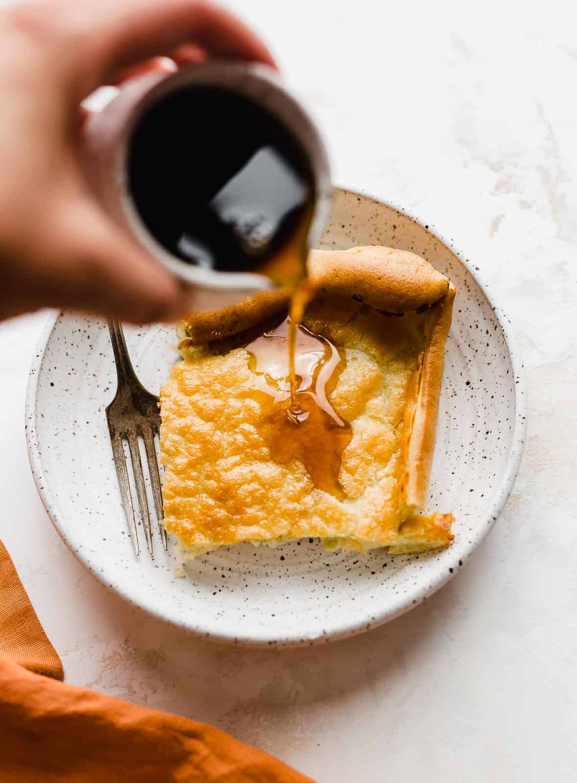 Brown maple syrup being poured overtop a German Pancake.