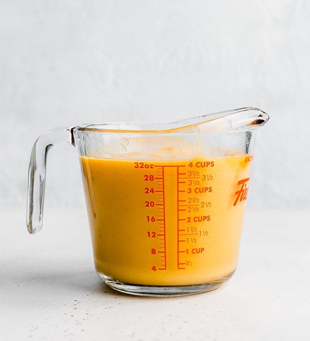 A 4 cup glass measuring cup full of pureed peaches.