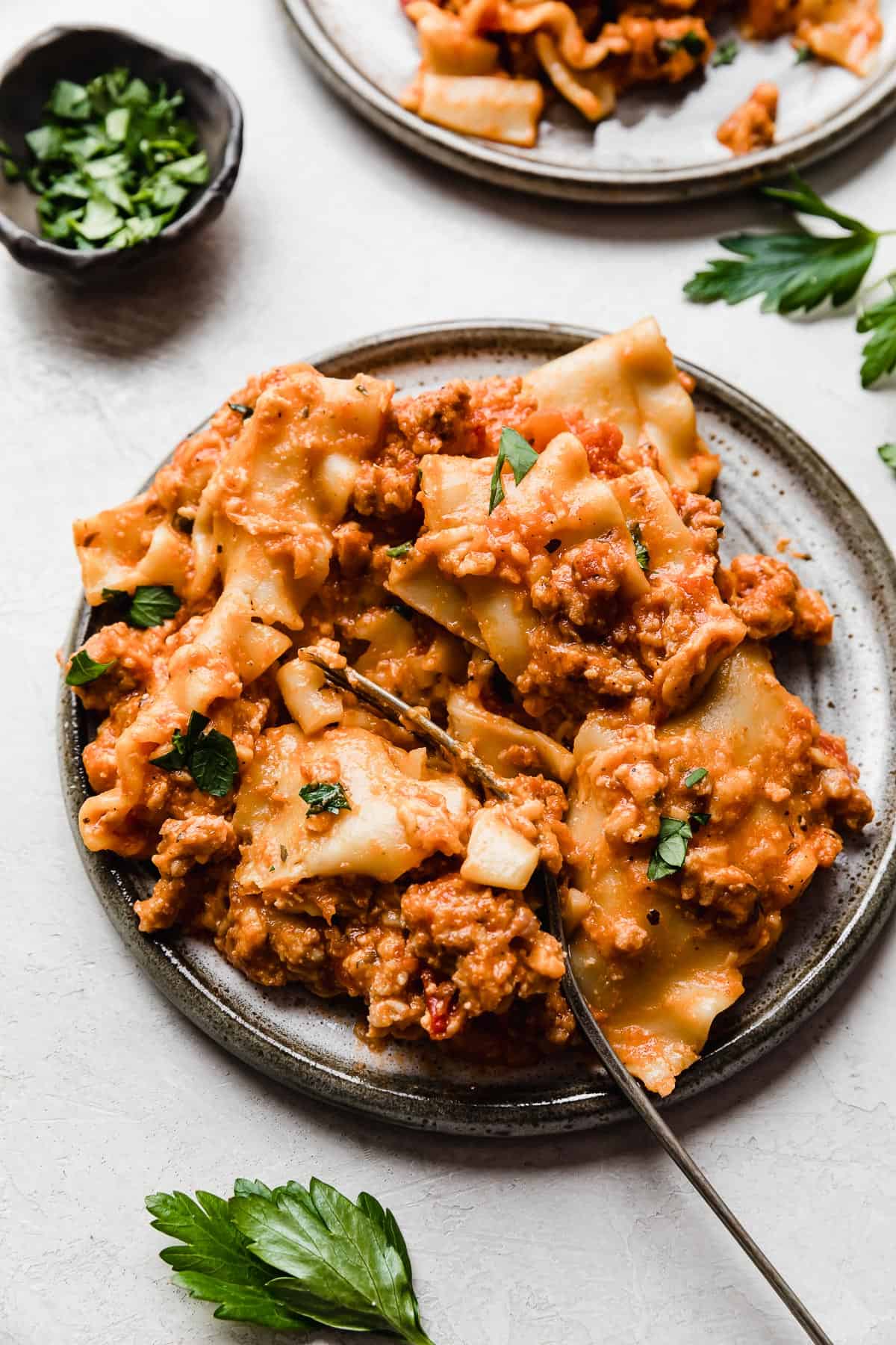 A serving of real simple Slow Cooker Lasagna on a gray plate on a white background.