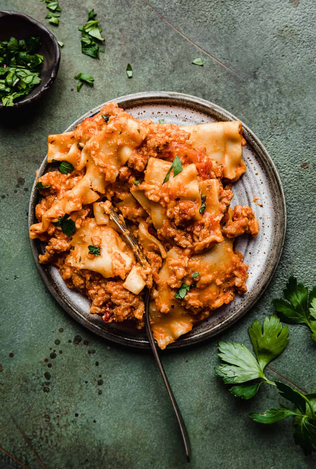 Lazy Slow Cooker Lasagna on a gray plate on a green background.