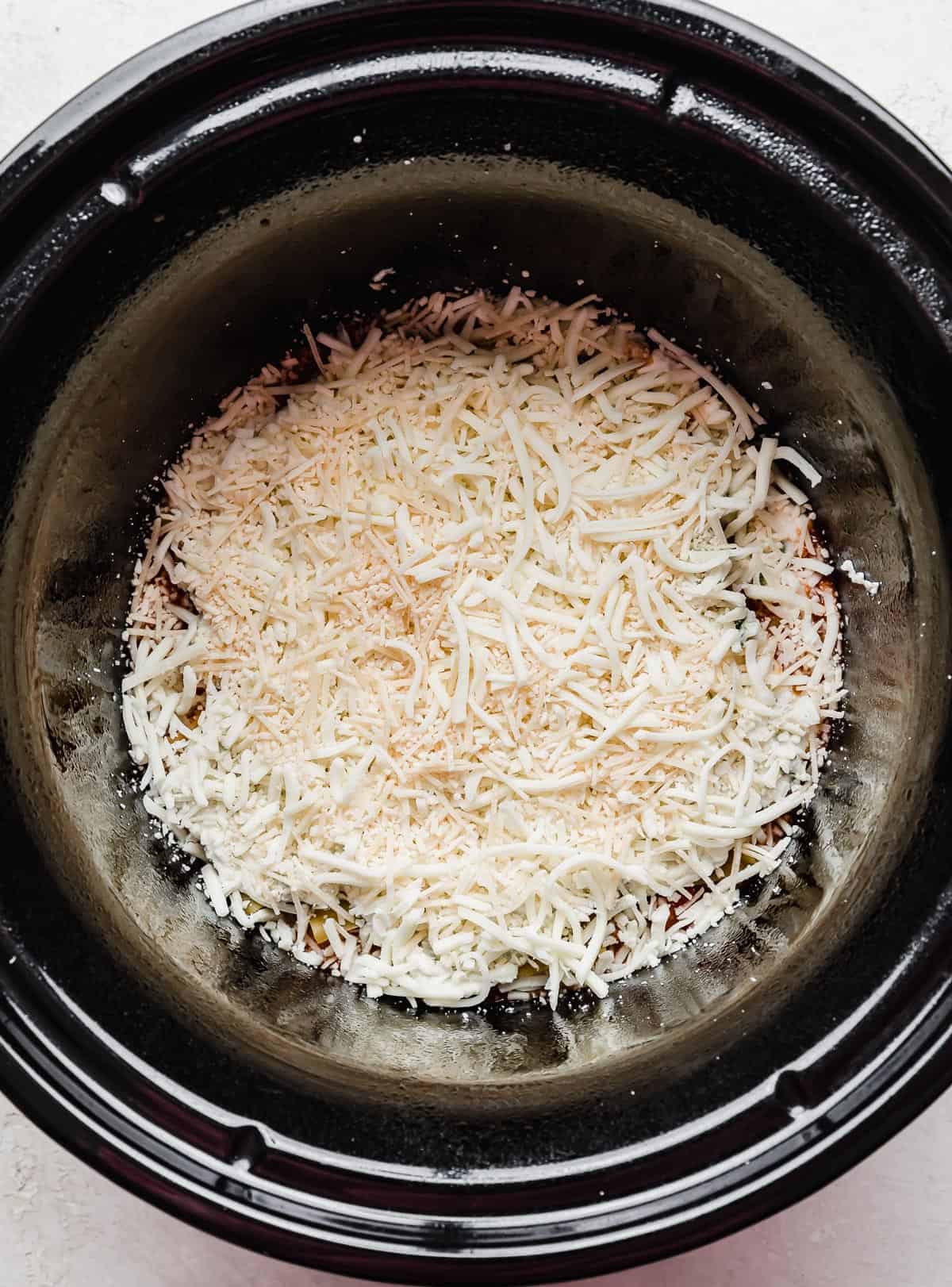 Shredded cheese in a round crock pot.