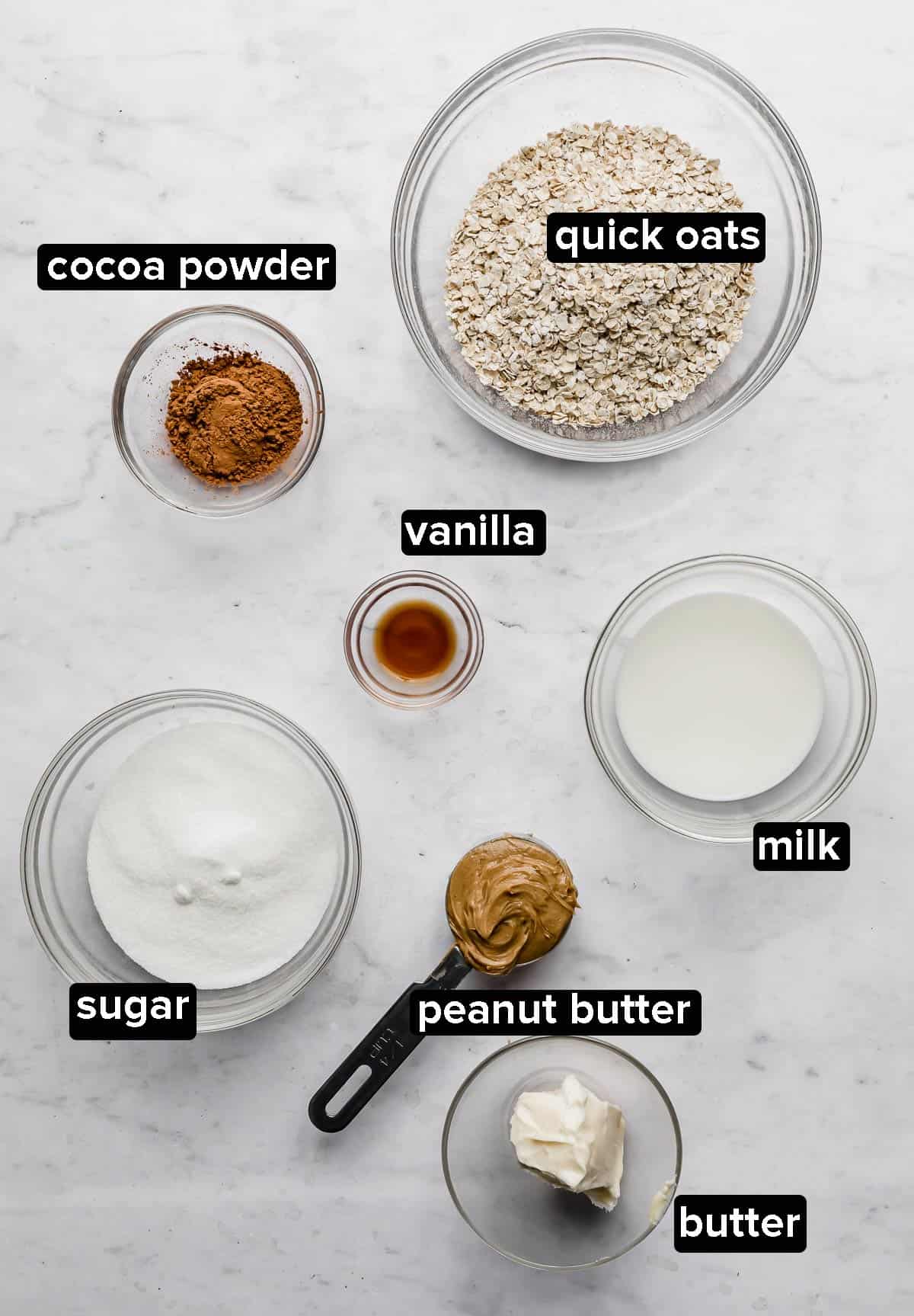Chocolate peanut butter oatmeal no bake cookies ingredients on a white marble background.