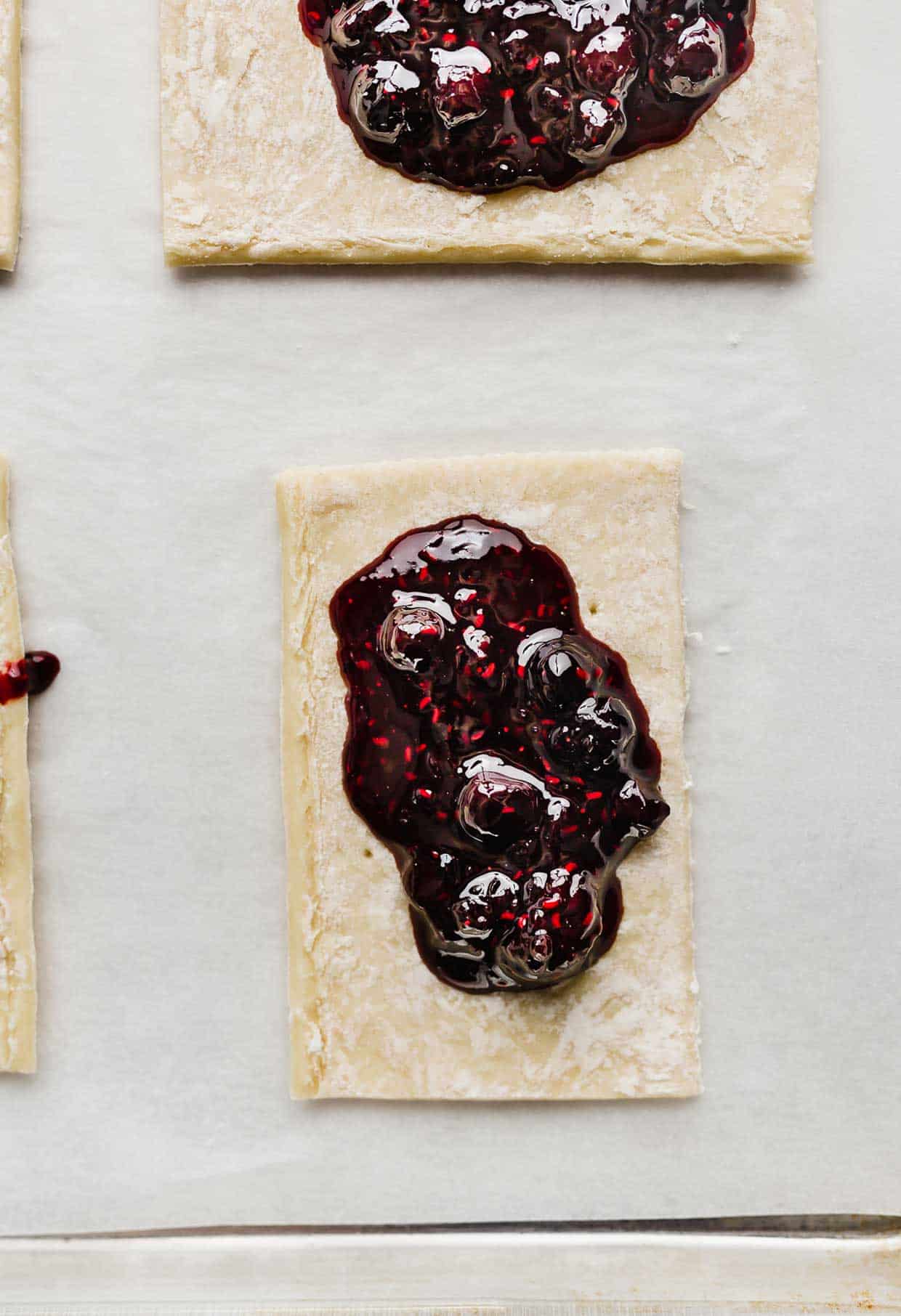 A triple berry jam dolloped in the center of a rectangular puff pastry sheet.