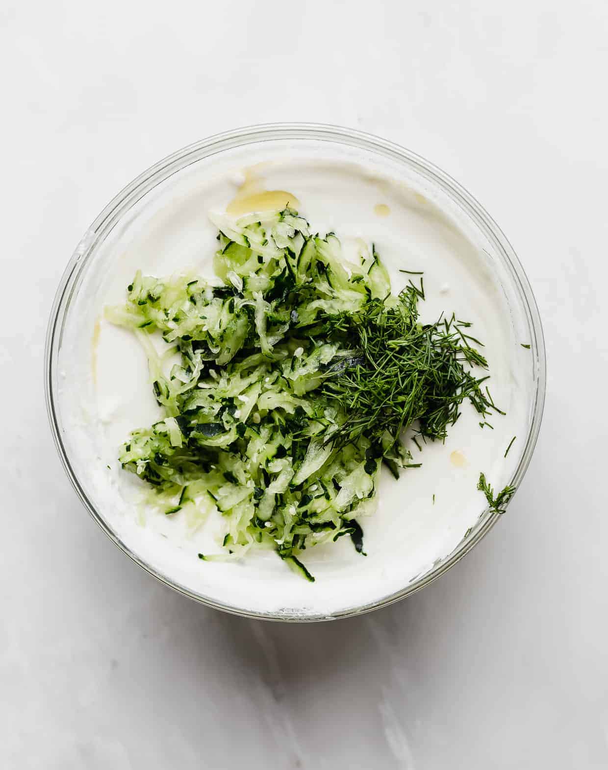 Tzatziki sauce in the making, fresh dill and shredded cucumber on top of Greek Yogurt. 
