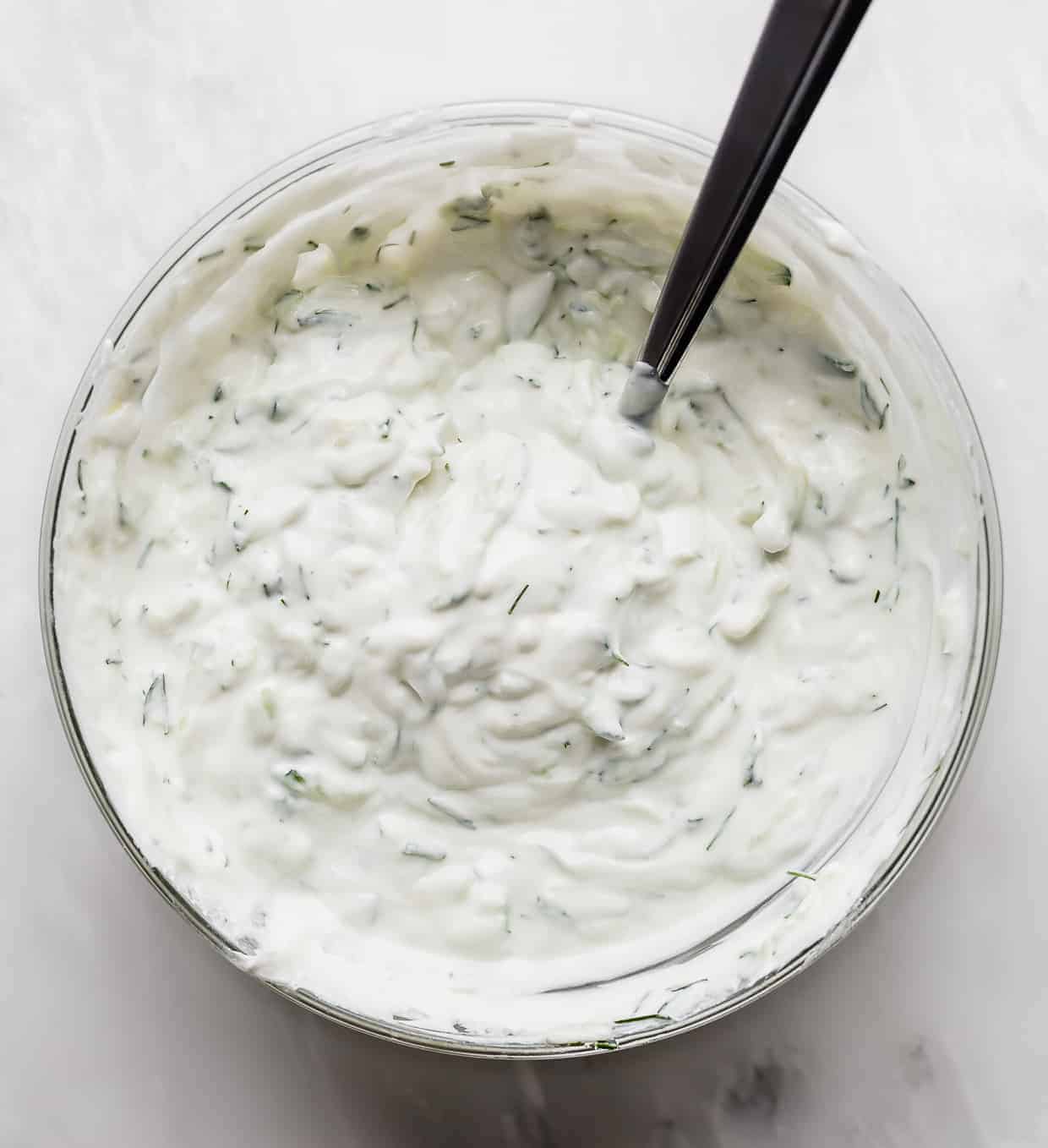 A bowl of Tzatziki sauce on a white background.