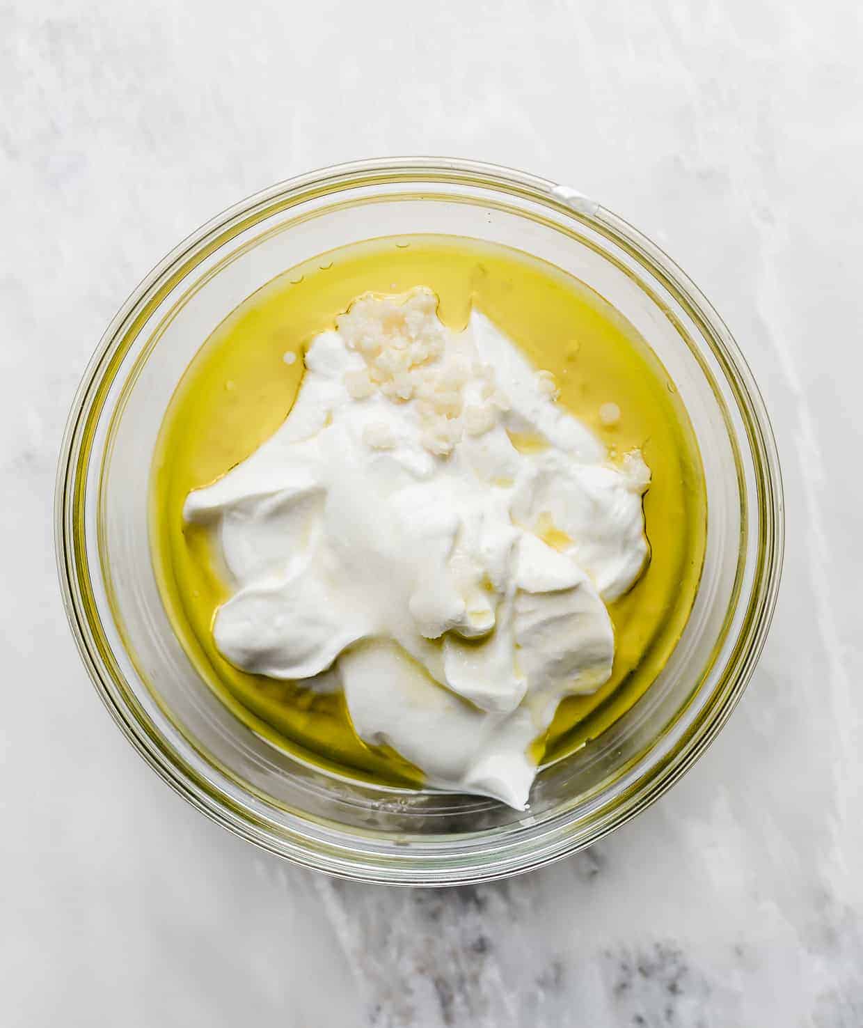 A bowl of full of Greek Yogurt, olive oil, and garlic.