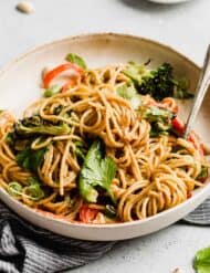 Peanut butter noodles with vegetables on a pasta plate.