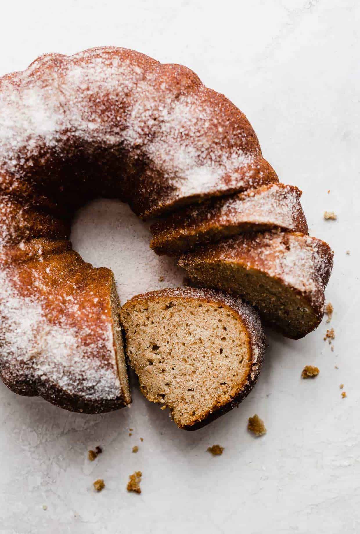 an apple cider coffee cake made in a bundt pan on a white background with three slices cut from the bundt cake.