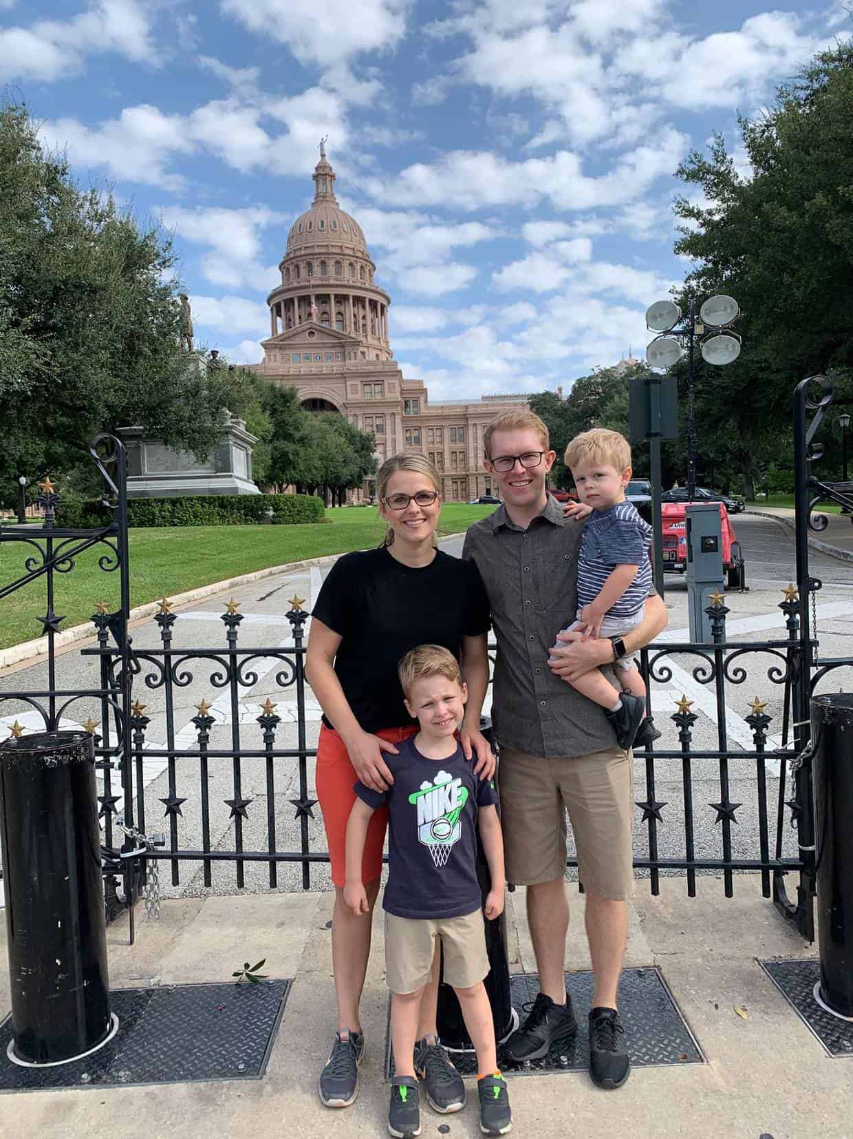 A family standing in front of the Austin Texas capitol.