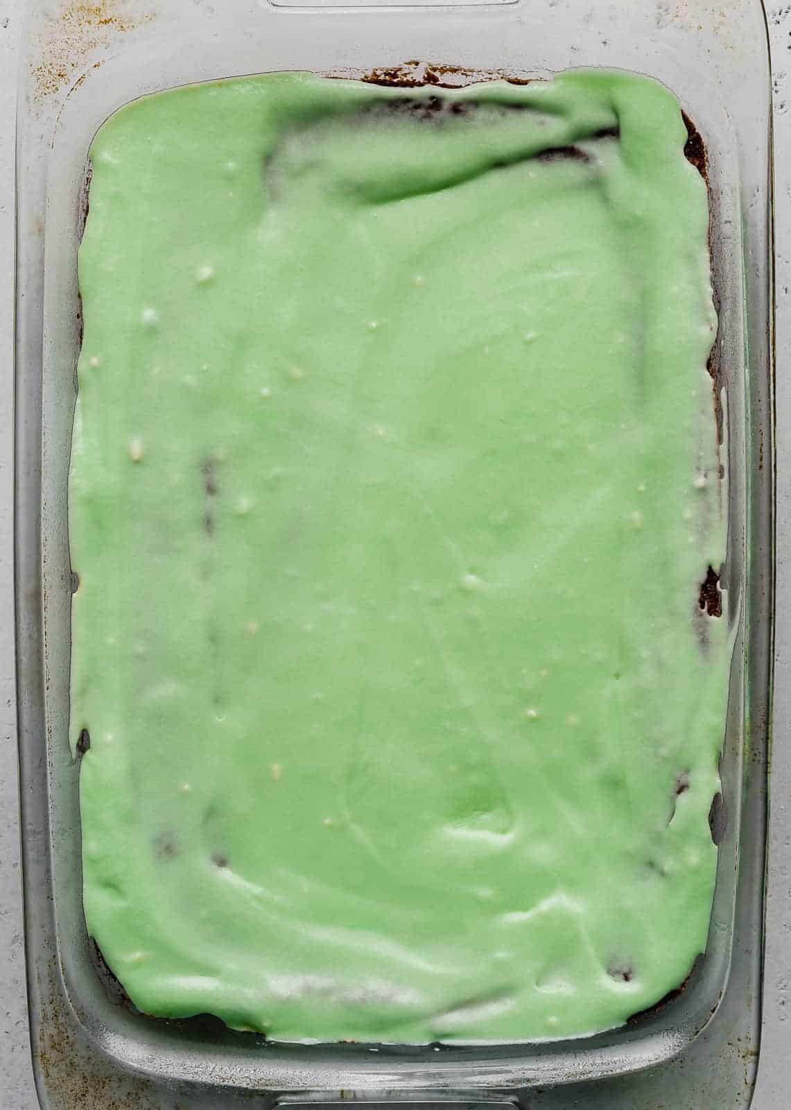 Green colored frosting spread over brownies.