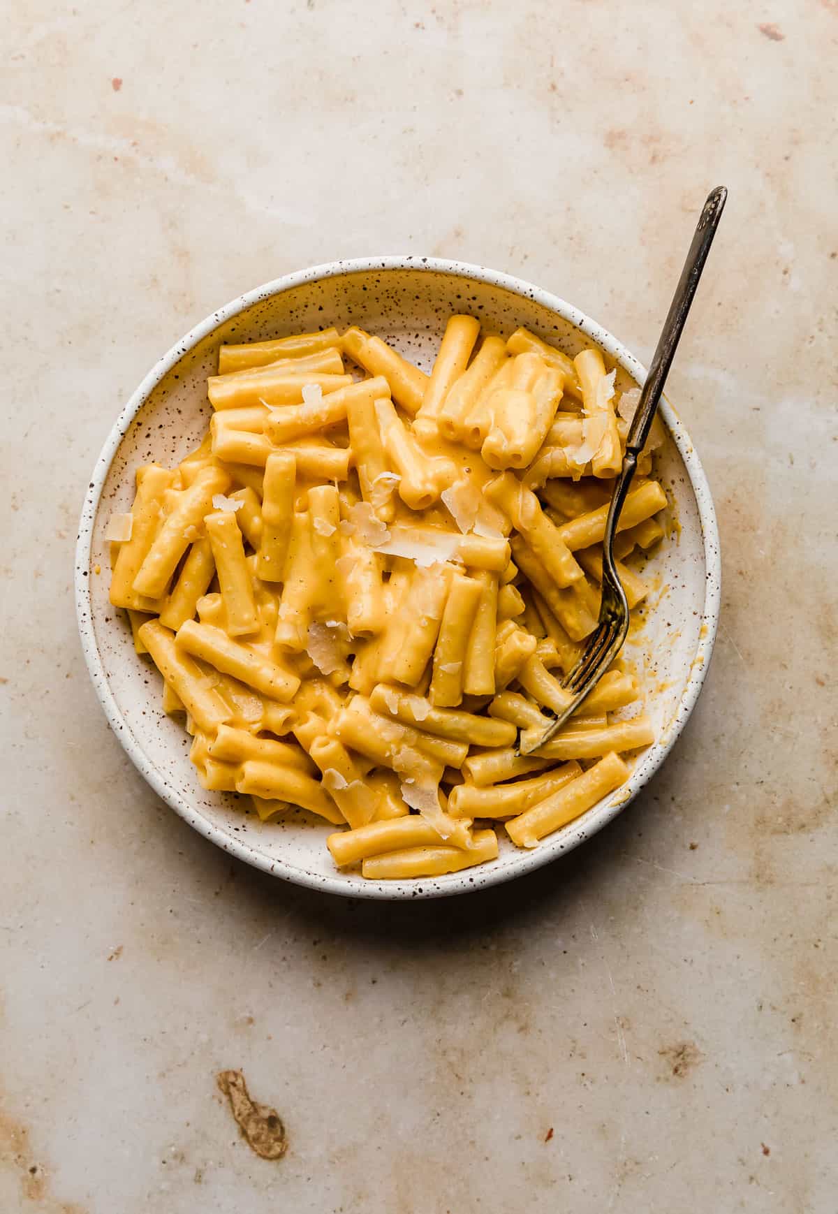 A white plate with creamy roasted Butternut Squash Pasta on it, against a tan marble background.