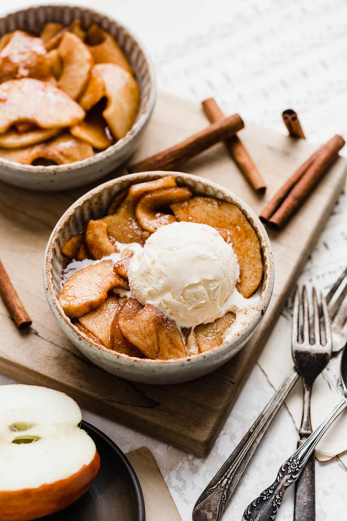 Cinnamon Baked Apples in a white bowl topped with a scoop of vanilla ice cream.