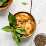 A bowl filled with Creamy Tomato Tortellini Soup with Spinach and topped with a sprig of fresh basil.