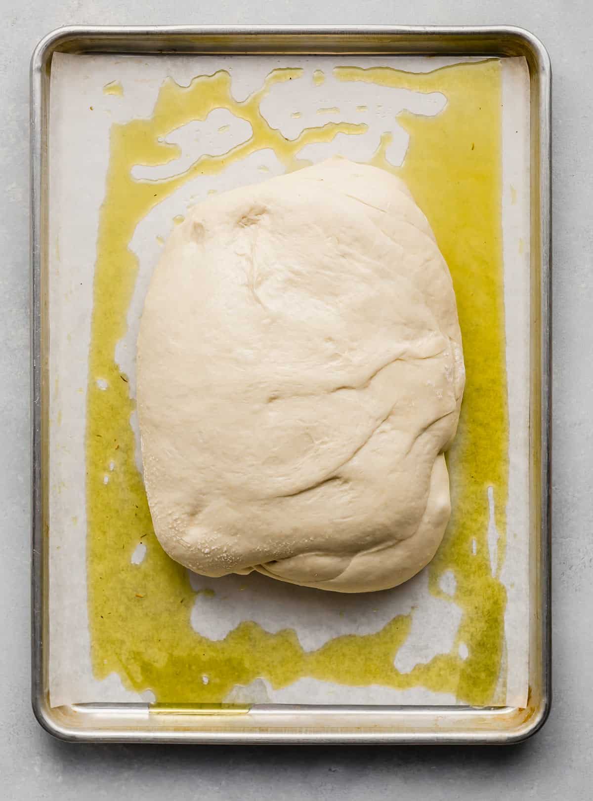 Focaccia Bread dough shaped in a rectangle on an oil covered baking sheet.
