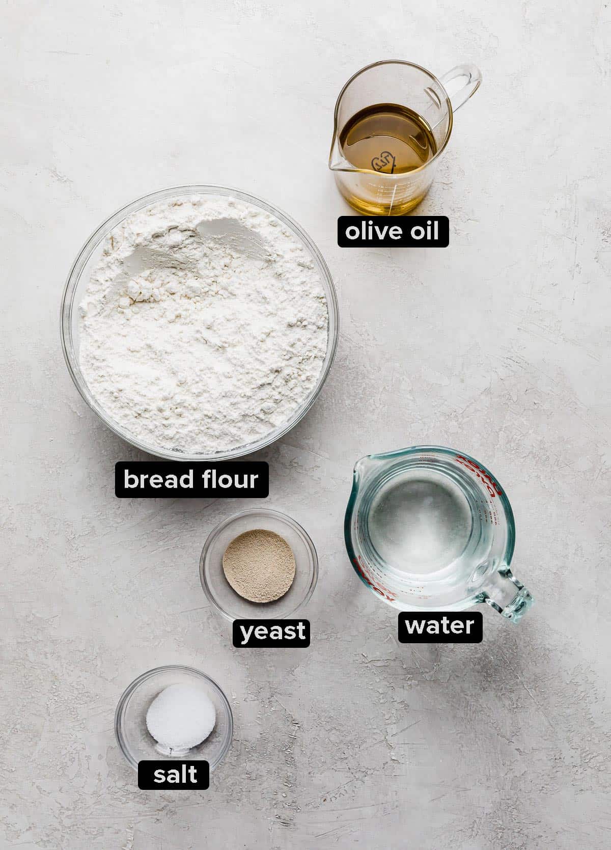 Focaccia Bread ingredients on a textured white background.