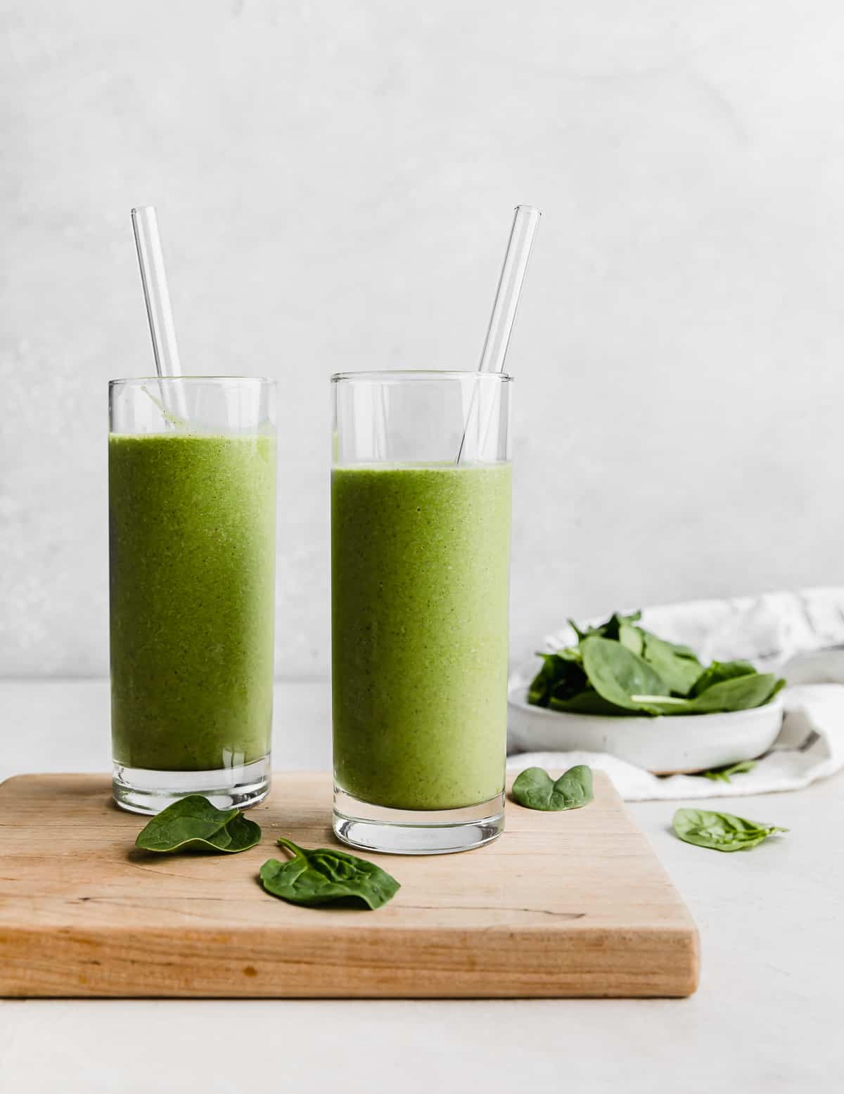 Two tall glasses full of Green Protein Smoothie against a white background.