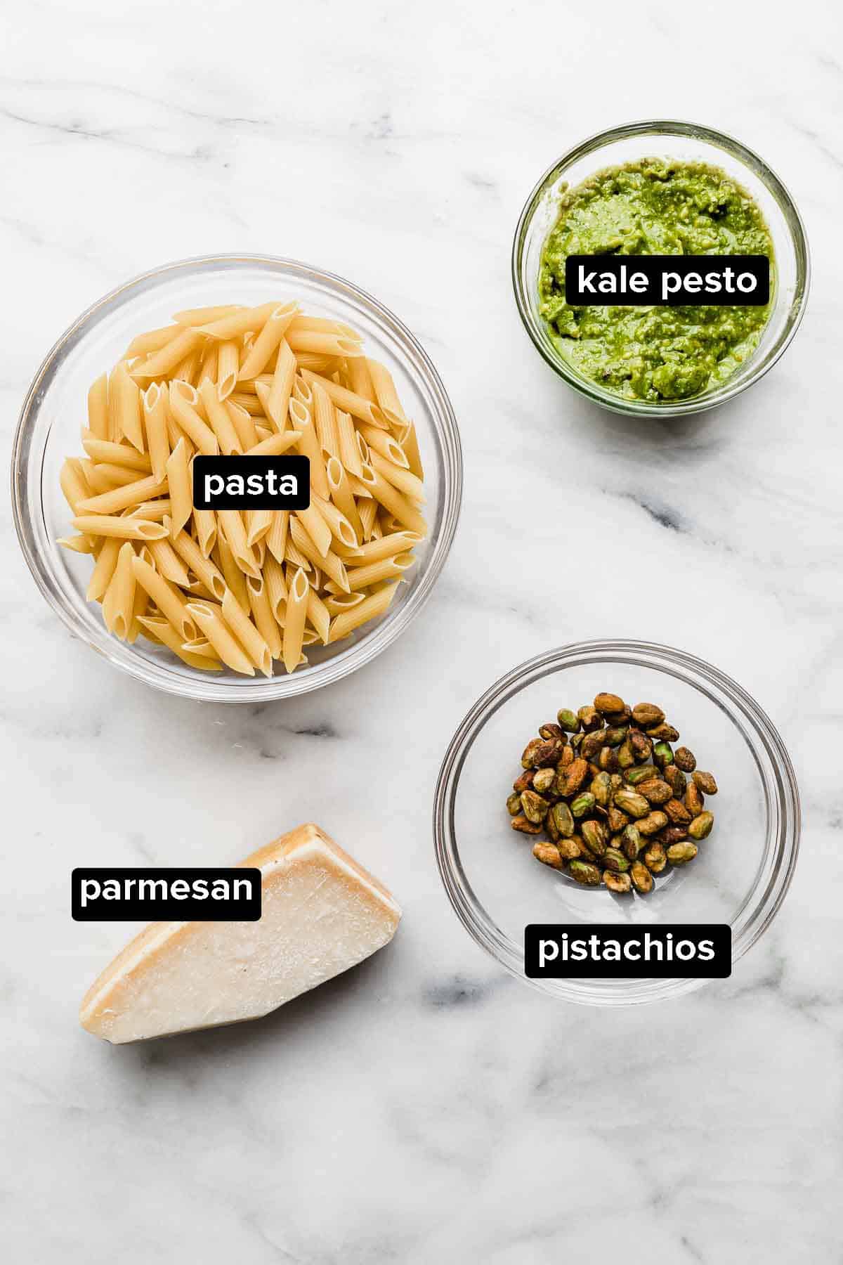 Kale Pesto Pasta ingredients on a white background (kale pesto, noodles, pistachios, parmesan). 