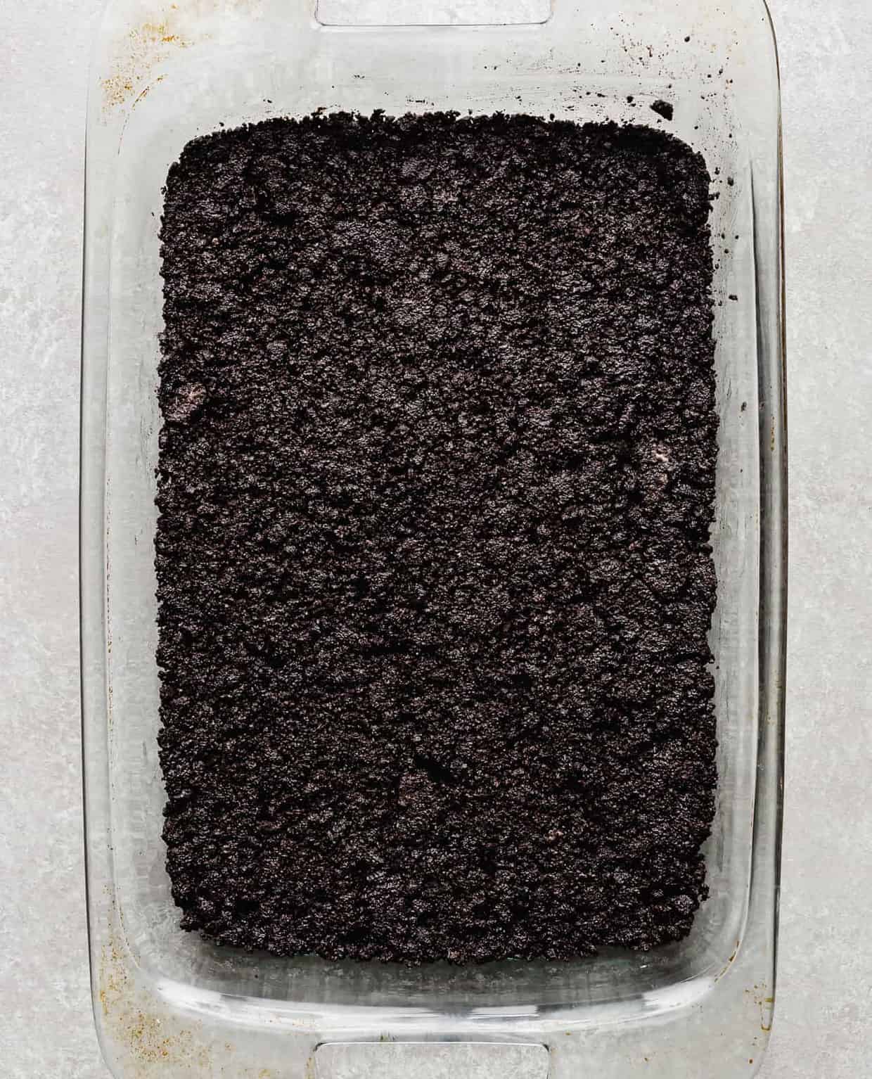 An oreo crust filling the bottom of a 13 inch by 9 inch pan.