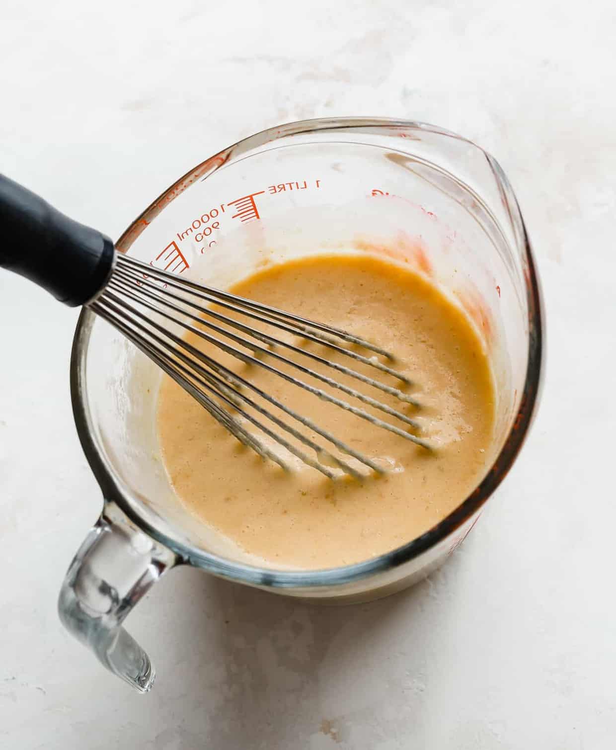 A glass measuring cup full of pumpkin puree, buttermilk, egg yolks, and butter.