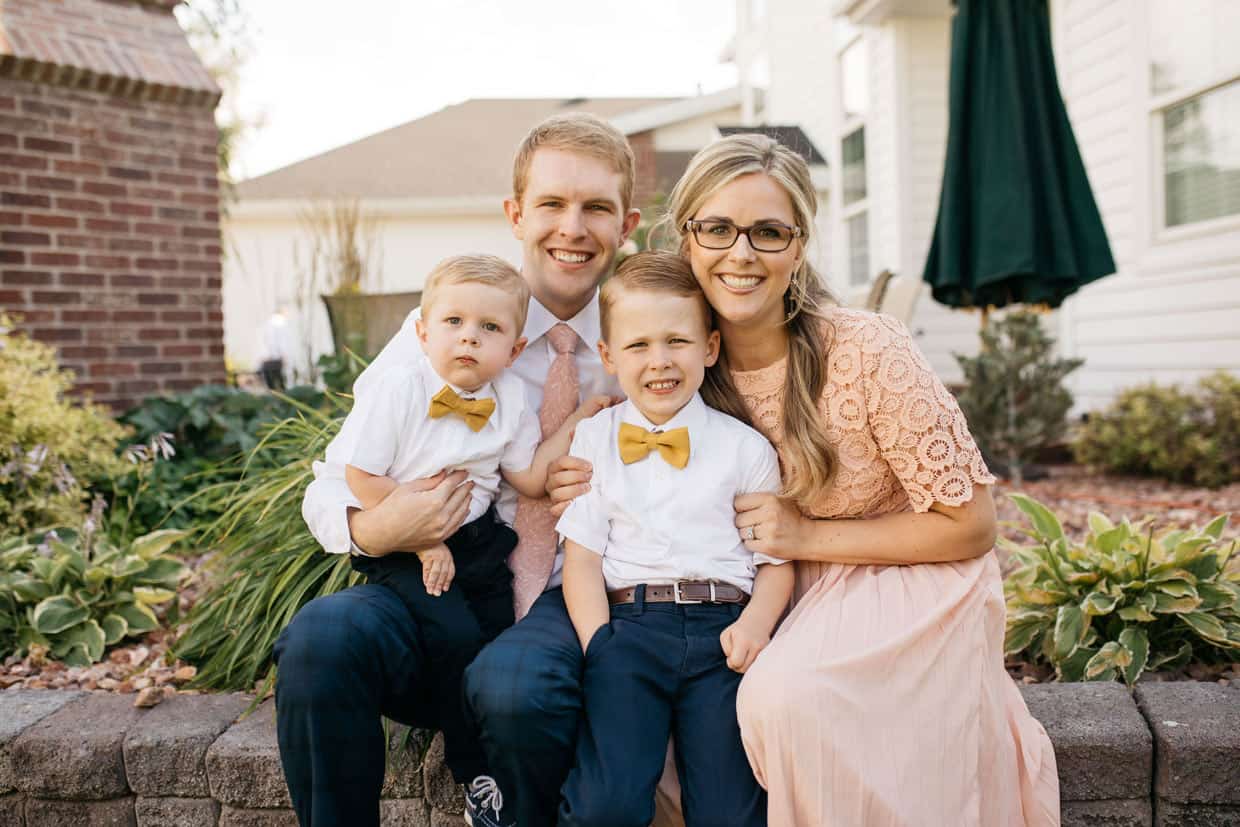 A husband and wife holding two young boys.