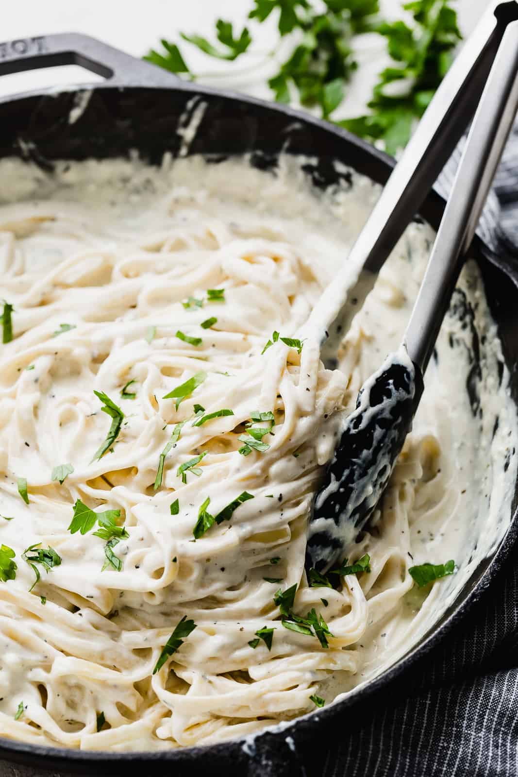 Fettuccini Alfredo in a black skillet topped with parsley.