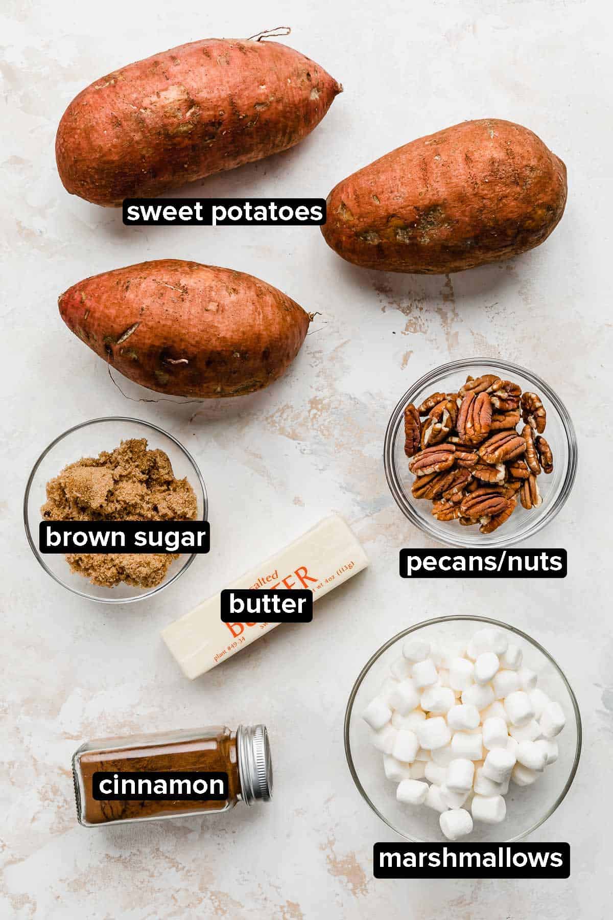 Baked Sweet Potato ingredients and sweet potato topping ideas on a white background: marshmallows, cinnamon, butter, nuts, brown sugar.