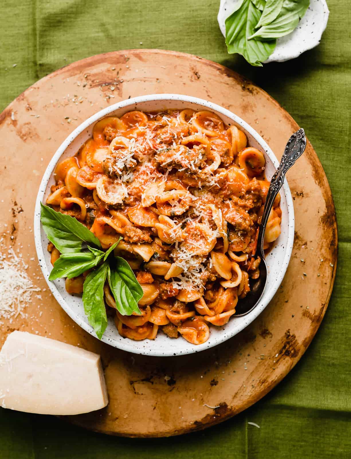 Bolognese sauce tossed with noodles, in a large white bowl. 