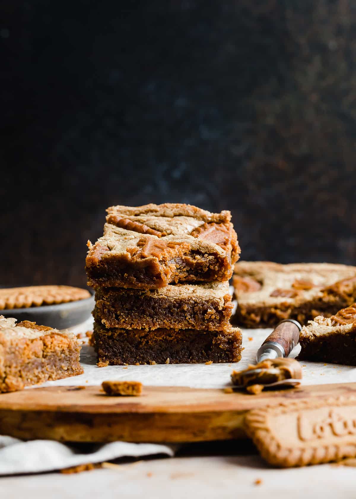 Three Biscoff Brownies stacked on top of each other in front of a black background.