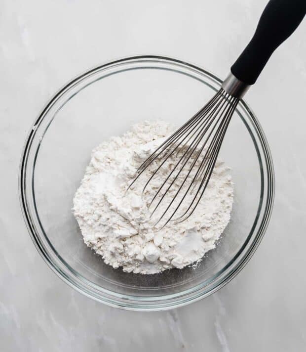 Flour and a whisk in a glass bowl.