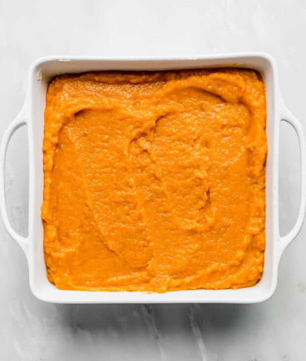 A square pan with mashed sweet potato casserole in it.