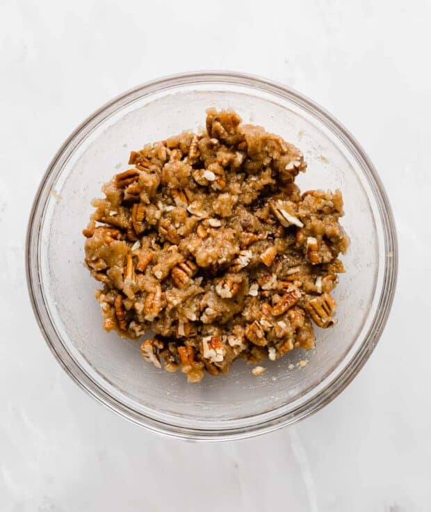 A glass bowl with a pecan crumble topping in it.