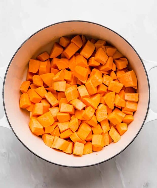 A dutch oven with cubed sweet potatoes in it.
