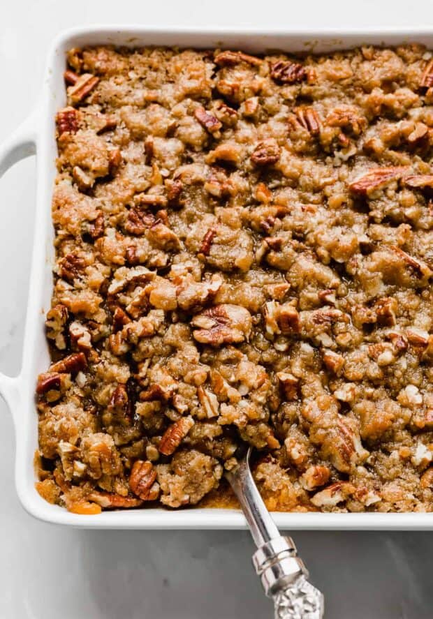 A large serving spoon scooping into a sweet potato casserole. 