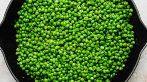 A skillet full of perfectly cooked green peas.