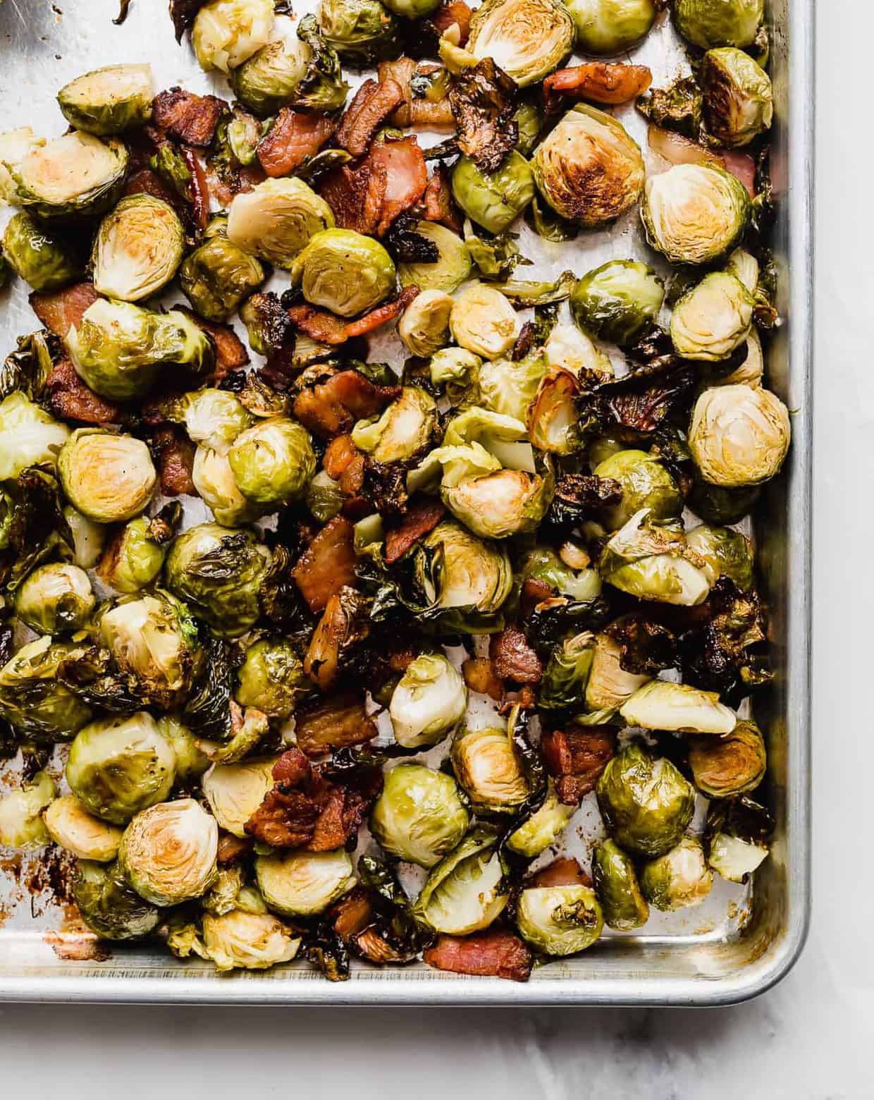 roasted Brussels sprouts and crispy bacon on a baking sheet.