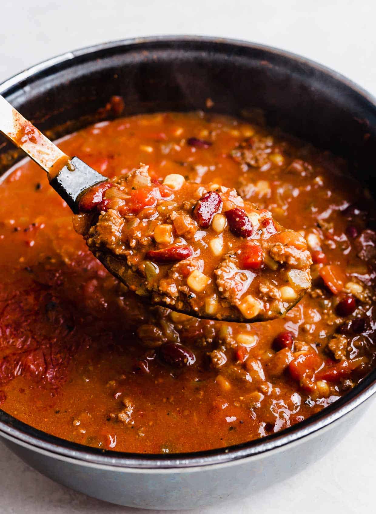 A serving spoon scooping up Taco Soup with Fritos.