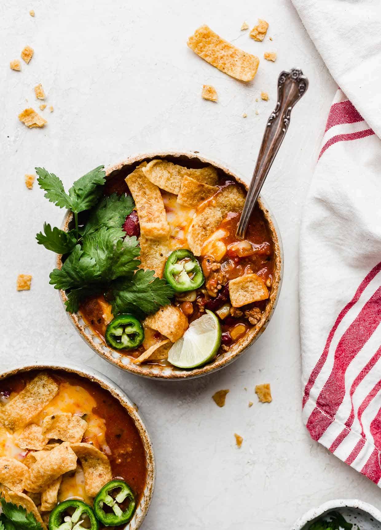 Overhead photo of a bowl of Taco Soup with Fritos and cilantro and lime wedge for garnish.