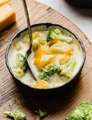 A bowl of cheesy Broccoli Potato Soup in a black rimmed bowl.