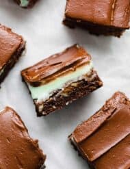 A BYU Mint Brownie cut into a square showing the brownie layer, mint frosting, and chocolate frosting layer.