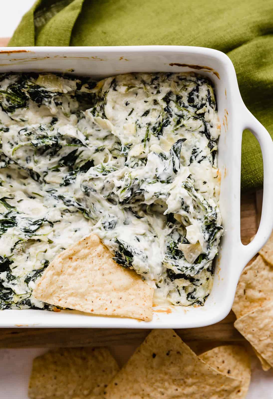 A chip dipped into warm spinach artichoke dip.